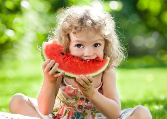 Young girl eating taking a bite of watermelon
