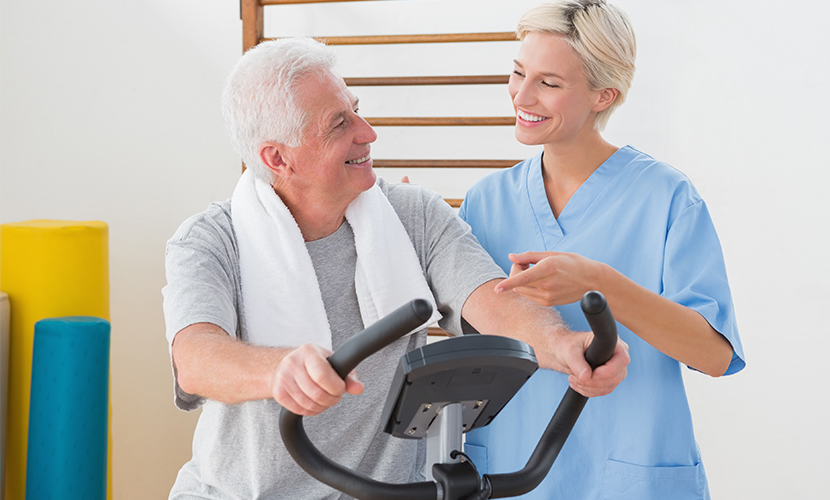 Rehab therapist talking to patient on exercise bike