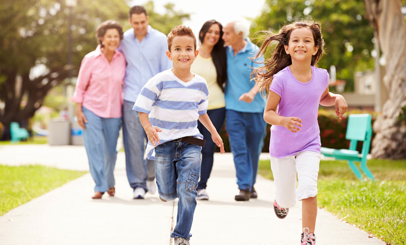 kids running ahead of parents and grandparents on sidewalk