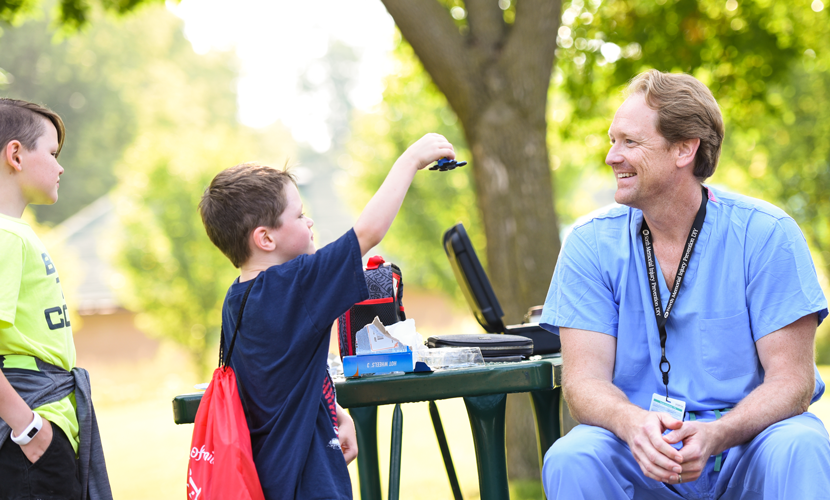 two boys with doctor on picnic table