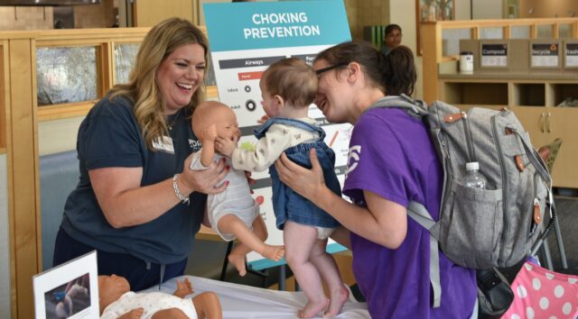 Mother and baby talking to Maple Grove Hospital team member at the World Breastfeeding Event at the hospital.